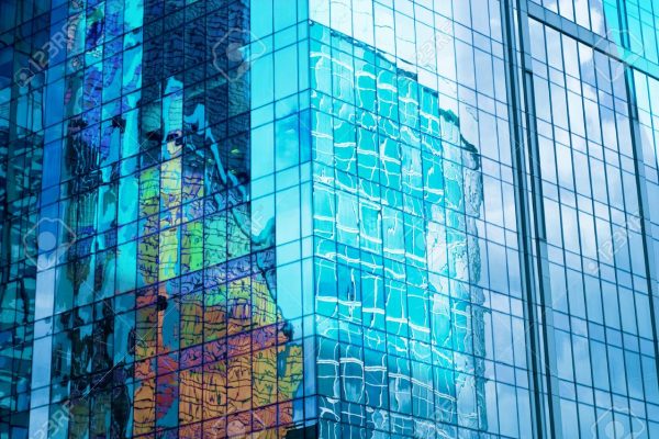 Glass wall of business center, reflection of buildings, business background, business concept