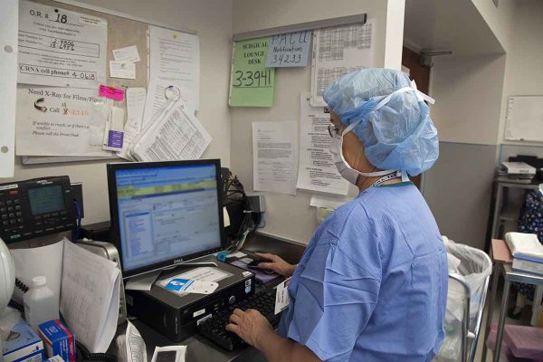 Operating Room Nurse Enters Data on Computer